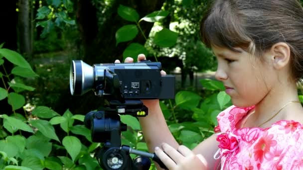 어린 소녀 녹색 공원 배경 배경 비디오 카메라에 보이는. — 비디오