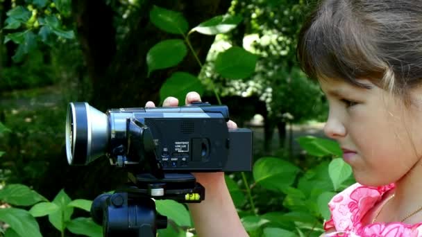 Mladá dívka vypadá na video kameru na pozadí pozadí zelený park. — Stock video