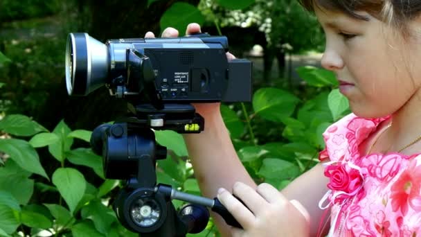 Fiatal lány úgy néz ki, a videó kamera a háttér-háttér zöld park. — Stock videók