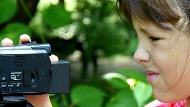 Mladá dívka vypadá na video kameru na pozadí pozadí zelený park. — Stock video