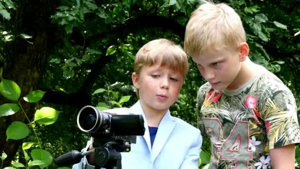 Młodzi chłopcy z kamerą wideo strzela film o charakter tło zielony park. — Wideo stockowe