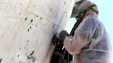 İşçiler tersanede tamirat sürecinde metali boyayla parçalıyorlar..