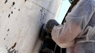 İşçiler tersanede tamirat sürecinde metali boyayla parçalıyorlar..