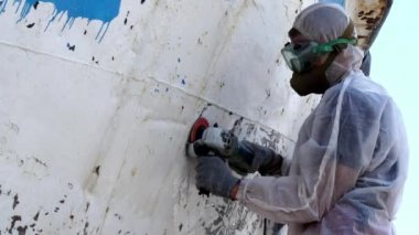 İşçiler tersanede tamirat sürecinde metali boyayla parçalıyorlar..