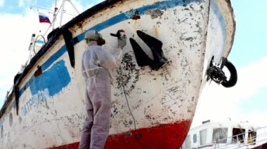 İşçiler tersanede tamirat sürecinde metali boyayla parçalıyorlar..