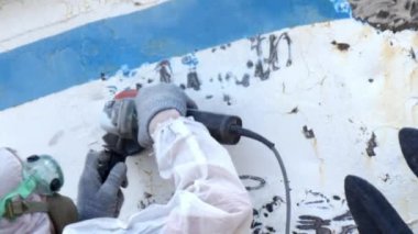 İşçiler tersanede tamirat sürecinde metali boyayla parçalıyorlar..