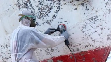 İşçiler tersanede tamirat sürecinde metali boyayla parçalıyorlar..