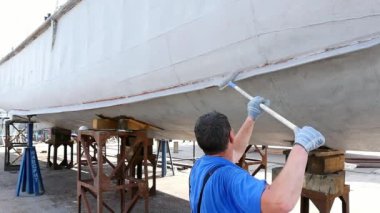 Çalışan eski paslı gemi pervane bağlantı noktası tersanesinde metalden boyar. Onarım ve deniz gemi inşası süreci. El ile resim teknelerin teknoloji. Su ulaştırma araçları sanayi.