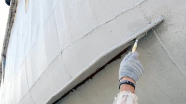 Çalışan eski paslı gemi pervane bağlantı noktası tersanesinde metalden boyar. Onarım ve deniz gemi inşası süreci. El ile resim teknelerin teknoloji. Su ulaştırma araçları sanayi.