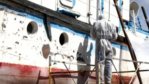 Workers tear off paint on metal in repairs process at shipyard. — Stock Video