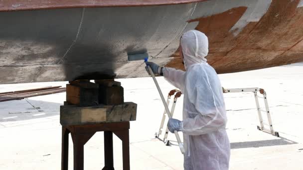 Un ouvrier peint le métal d'une vieille hélice rouillée au chantier naval du port . — Video