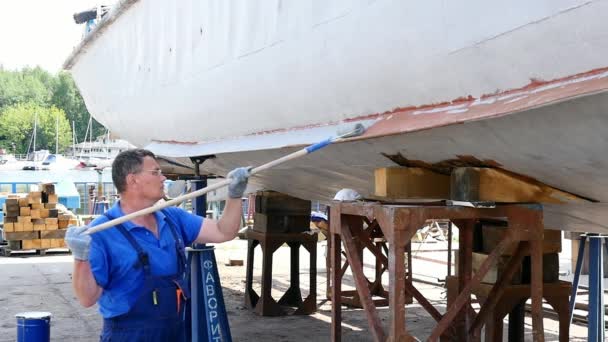 Trabajador pinta metal de vieja hélice de barco oxidado en astillero en puerto . — Vídeos de Stock