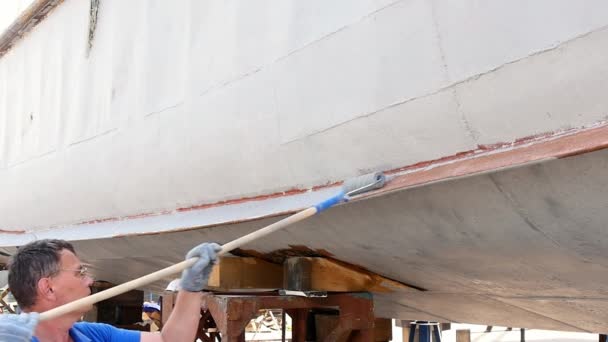 Worker paints metal of old rusty ship propeller at shipyard in port. — Stock Video