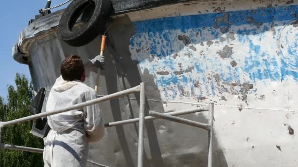 Un ouvrier peint le métal d'une vieille hélice rouillée au chantier naval du port . — Video