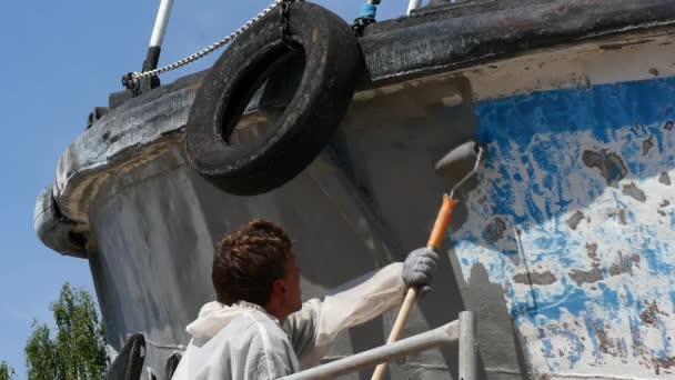 Trabajador pinta metal de vieja hélice de barco oxidado en astillero en puerto . — Vídeo de stock