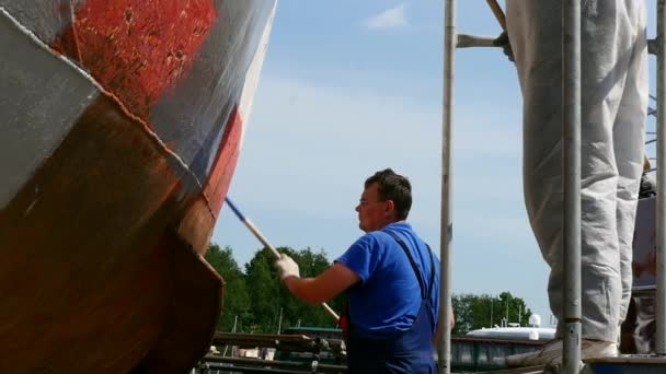 Arbetaren målar metall av gammal rostig fartyget propeller på varvet i hamn. — Stockvideo