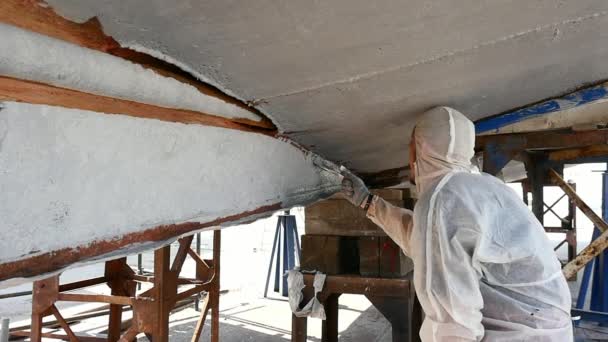 Pracovní maluje kartáč kovový přední lodi v loděnici v přístavu v Moskvě. — Stock video