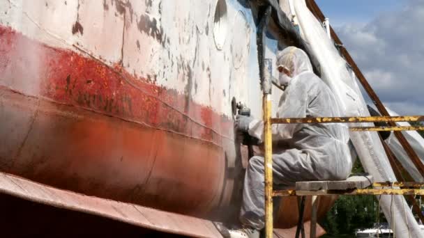 Working people tear off paint on metal in repairs process at shipyard. — Stock Video