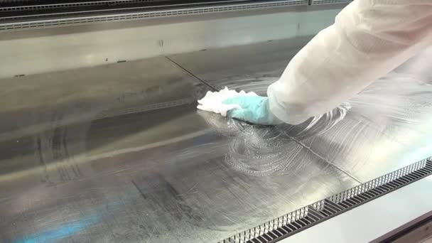Рука работника в перчатке чистит витрину холодильника в супермаркете . — стоковое видео