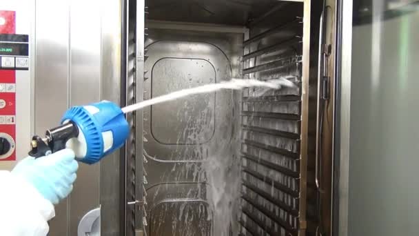 Hand of worker in glove with blue cleaning gun washes industrial oven. — Stock Video