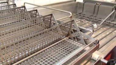 İşçinin elinde parlak sarı fırça endüstriyel fritöz temizler.