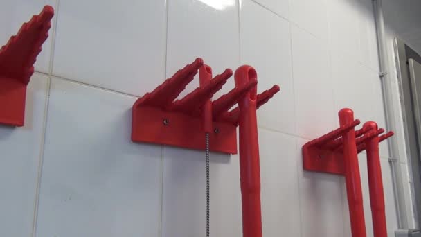 Cepillos industriales rojos en una pared blanca con azulejos y mano de trabajador en guante . — Vídeo de stock