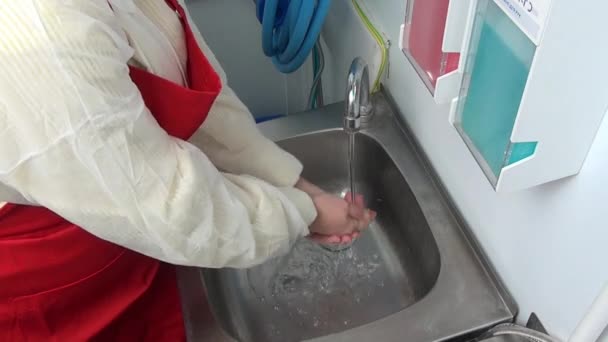 Arbeiterin in roter Schürze wäscht sich die Hände unter dem Wasserhahn. — Stockvideo