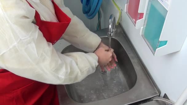 Mujer trabajadora en delantal rojo se lava las manos bajo el grifo . — Vídeos de Stock