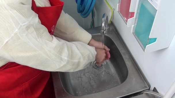 Γυναίκα εργαζόμενος στην κόκκινη ποδιά πλένει τα χέρια της κάτω από τη βρύση. — Αρχείο Βίντεο