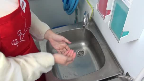 Arbeiterin in roter Schürze wäscht sich die Hände unter dem Wasserhahn. — Stockvideo