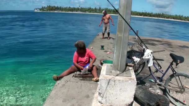 Человек чистит рыбу на берегу моря . — стоковое видео