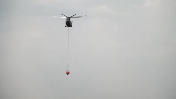 Helicóptero de carga con cucharón de vertedero suspendido está volando desde el depósito. — Vídeos de Stock