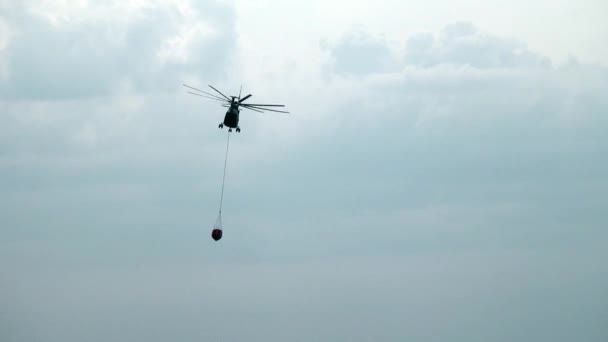 Frachtlöschhubschrauber mit aufgehängter Schöpfkelle fliegt von Stausee. — Stockvideo