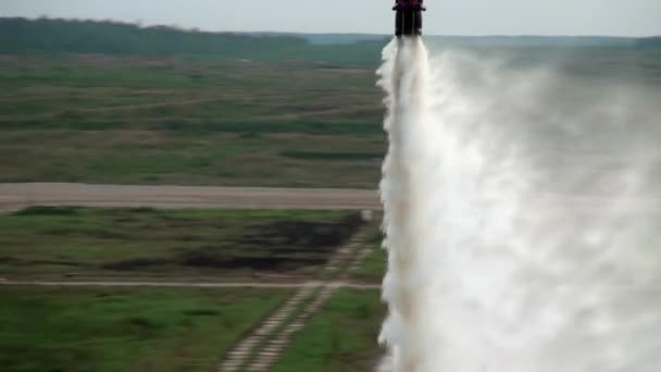 Scoop appeso rosso da un elicottero antincendio scarica acqua su sfondo grigio cielo . — Video Stock