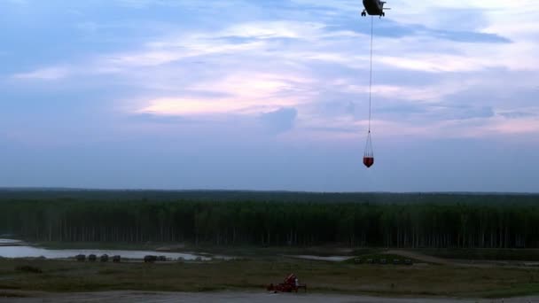 Cargo fire helicopter with suspended spillway ladle is flying from reservoir. — Stock Video