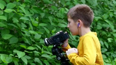 Genç çocuk video kamera ile film doğa hakkında yeşil park yavaş hareket üzerinde vuruyor..
