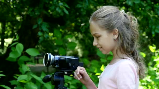 Young girl with video camera shoots movies in nature on green park slow motion. — Stock Video