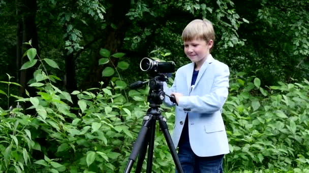 Jonge jongen kijkt in video scheuten film over aard op groen park slow motion. — Stockvideo