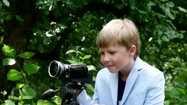 Giovane ragazzo con videocamera gira film sulla natura sul parco verde al rallentatore . — Video Stock