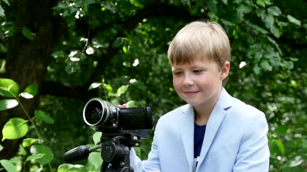 Giovane ragazzo guarda nella videocamera sullo sfondo del parco verde slow motion . — Video Stock