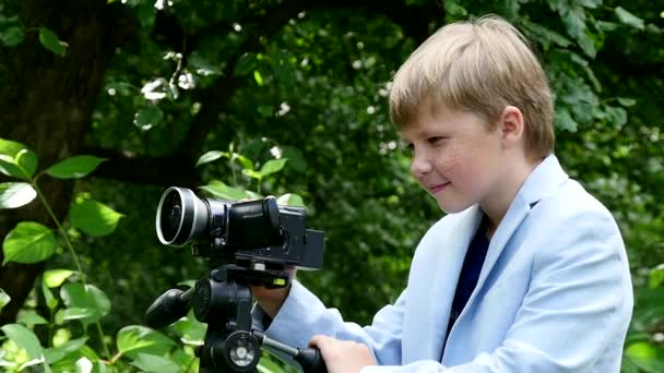 Kleiner Junge schaut in Video-Aufnahmen Film über die Natur auf grünen Park Zeitlupe. — Stockvideo