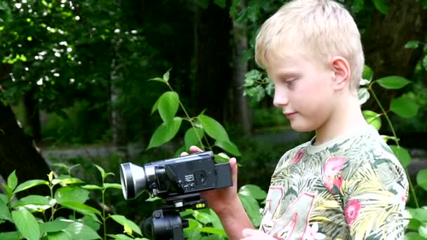 Giovane ragazzo con videocamera scatta film in natura del parco verde slow motion . — Video Stock