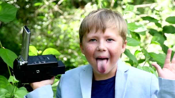 Mladík s videokamerou střílí film v přírodě zeleného parku zpomalené. — Stock video