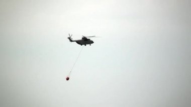 Sızıntı kepçesi askıya alınmış kargo yangın helikopteri rezervuardan uçuyor..
