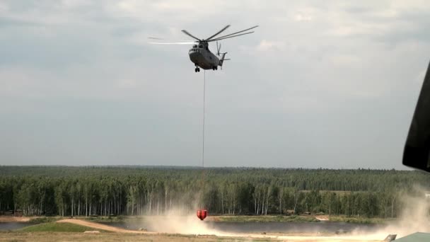 Hélicoptère d'incendie cargo avec poche anti-déversement suspendue vole à partir du réservoir. — Video