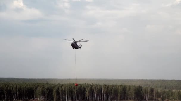Helikopter mit Hängekelle fliegt zum Stausee zur Wasseraufnahme. — Stockvideo