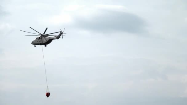 Frachtlöschhubschrauber mit aufgehängter Schöpfkelle fliegt von Stausee. — Stockvideo
