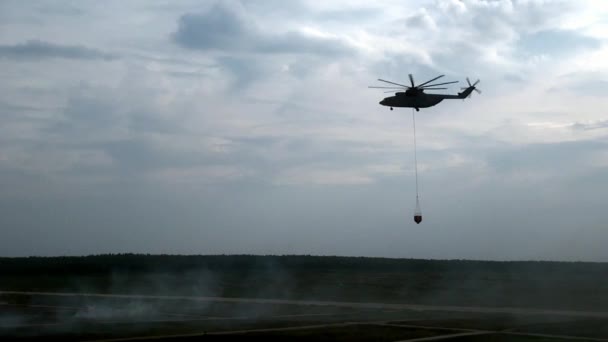 Helicóptero con cucharón de vertedero suspendido vuela al depósito para la ingesta de agua . — Vídeos de Stock