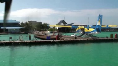 Sarı-mavi deniz uçağı standları okyanusta pier yakınındaki.