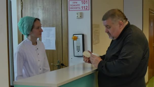 Enfermera toma tarjeta médica del gordo en la clínica . — Vídeo de stock